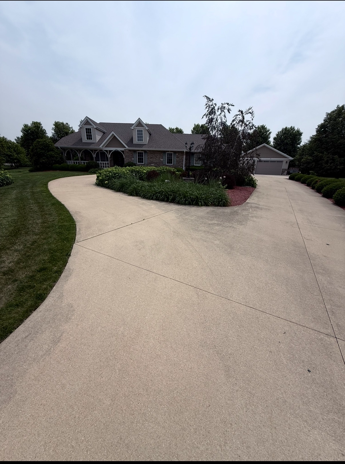 Curved concrete driveway before pressure washing