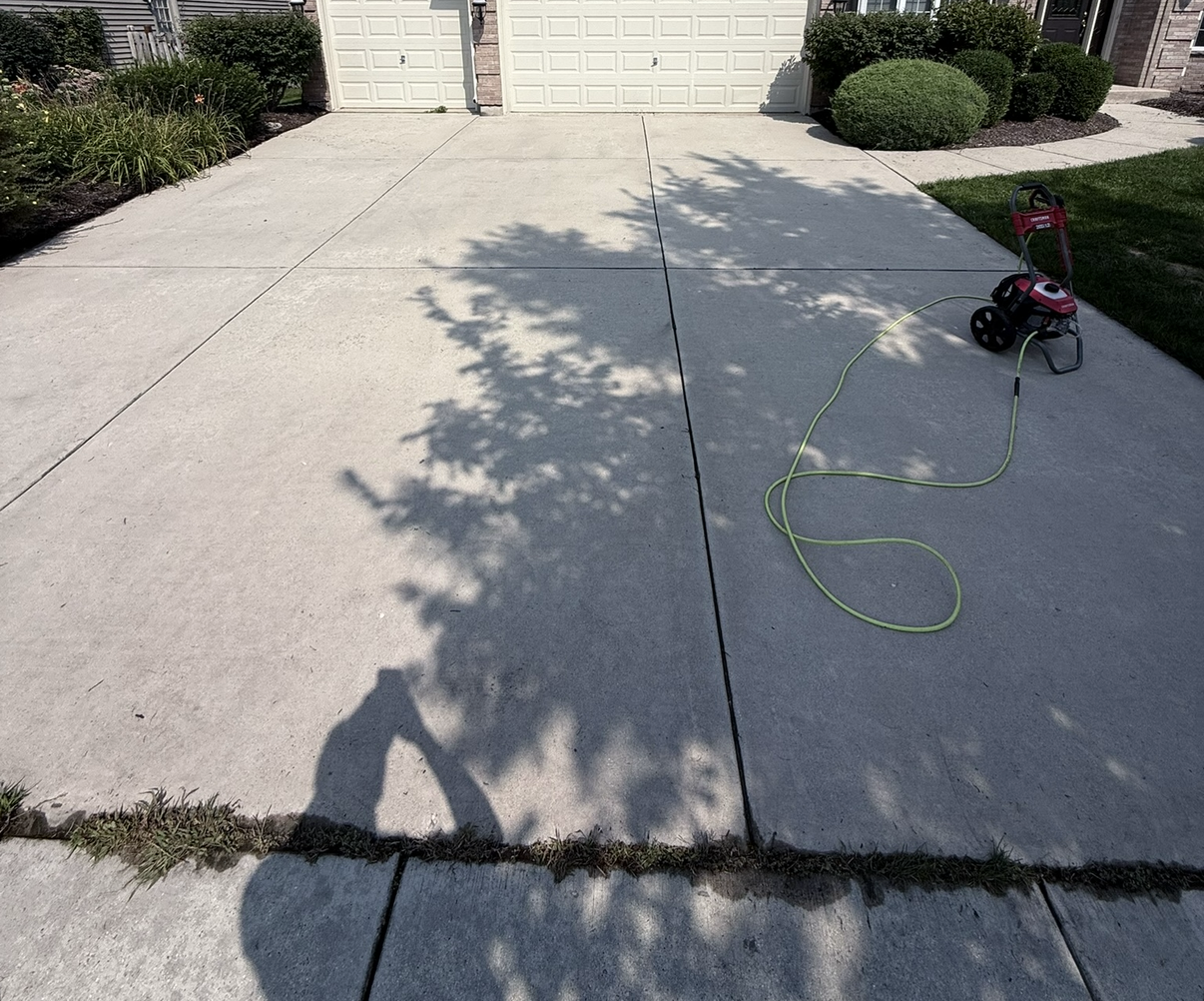 Clean driveway with pressure washer in foreground